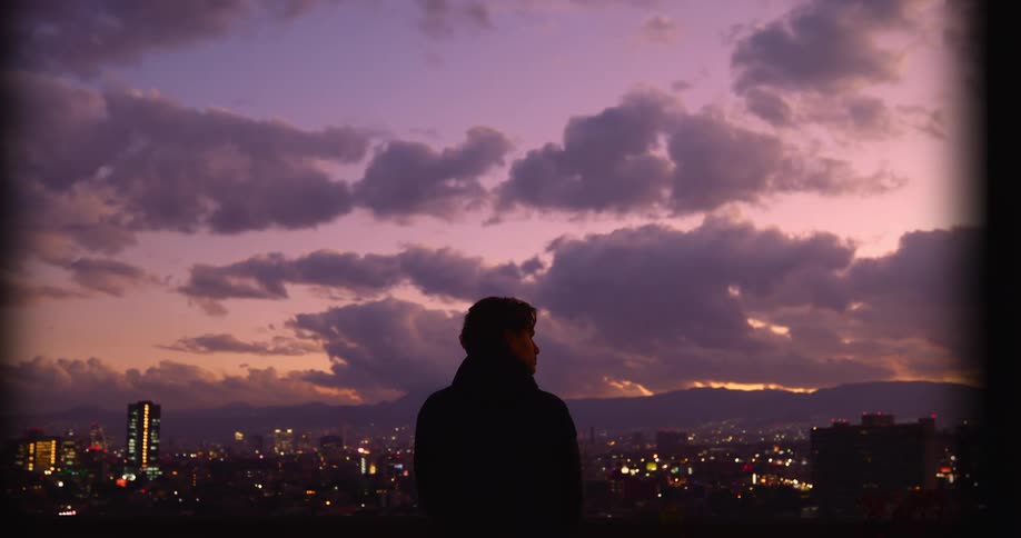 Man in front of an urban skyline at twilight