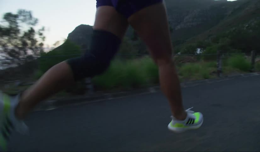 A closeup of a persons lower legs midstride while running on an asphalt road in the mountains