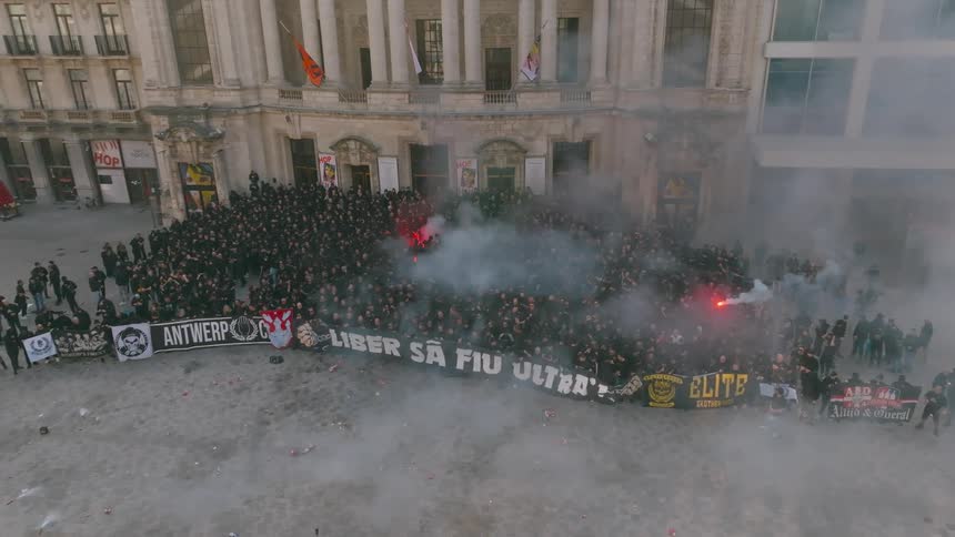 A large number of people protesters holding a huge sign and some people holding flares that are coming out of smoke