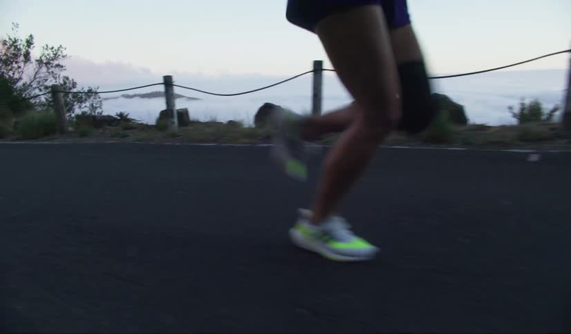 A persons lower legs running on an asphalt road over the clouds