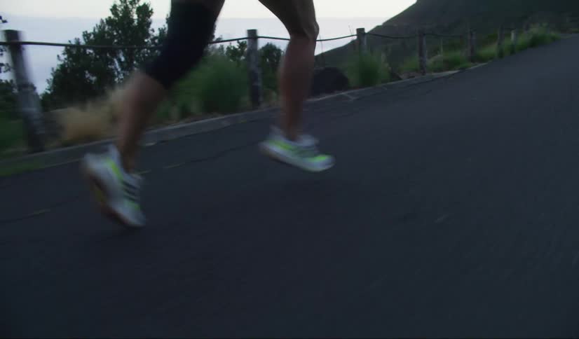 Runner in motion with focus on sneakers hitting the asphalt