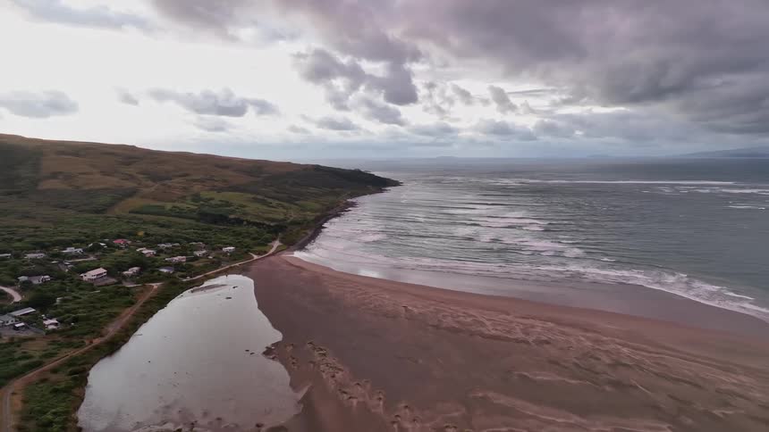 Aerial view of a coastal landscape with a cluster of buildings near the shore adjacent to a large body of water