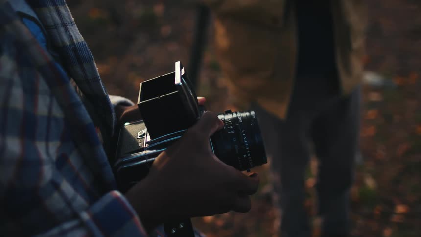 Two men playing with a vintage camera outdoors