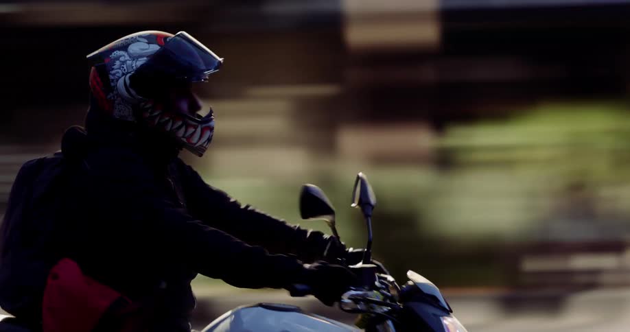 A person wearing a helmet with the visor open riding a white motorcycle