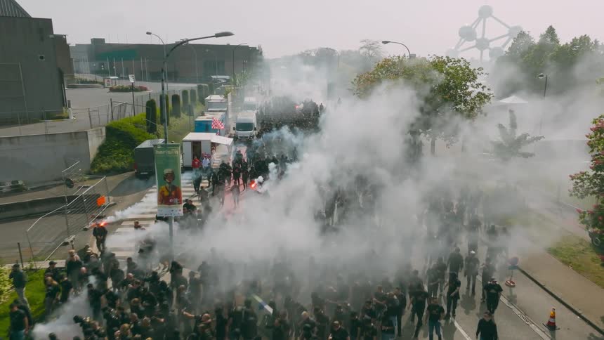 A group of individuals on a protest or demonstration in a street surrounded by smoke