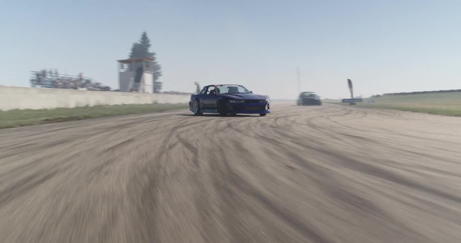 A blue race car drifting on the curve of a racetrack