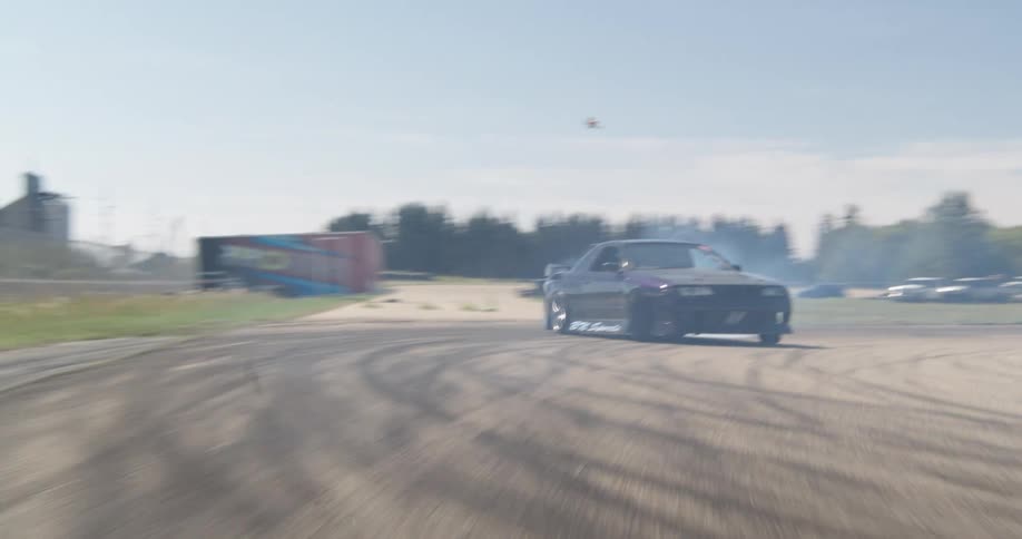A black car is racing around a race track by itself and heavily drifting