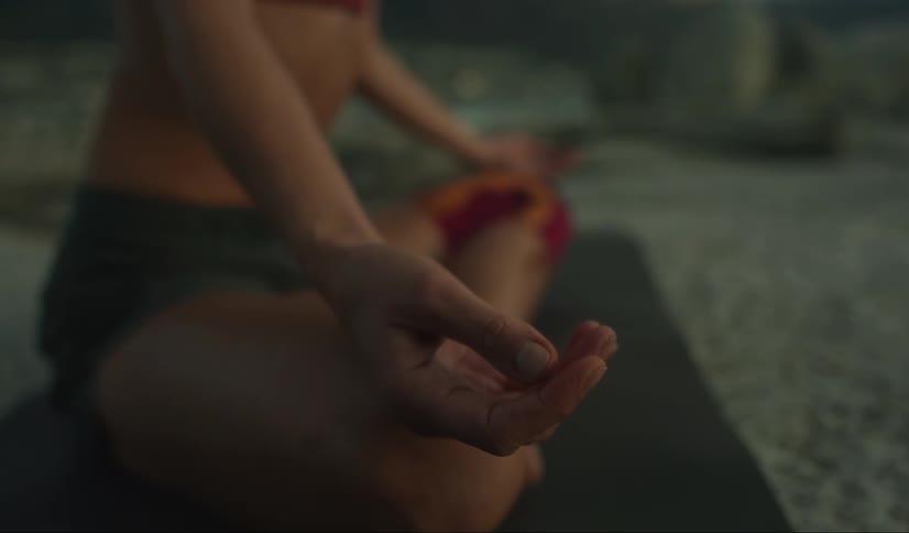 A woman sits on a mat while doing a yoga stretch