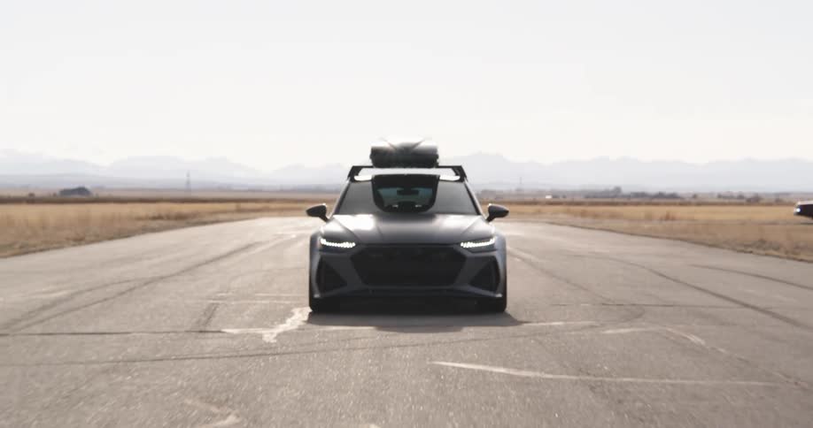 A car with a roof box is driving on a road or an airport tarmac