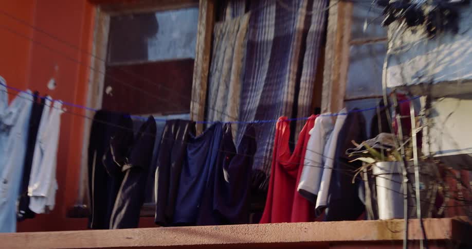 Various items of clothing hang on a line in a balcony