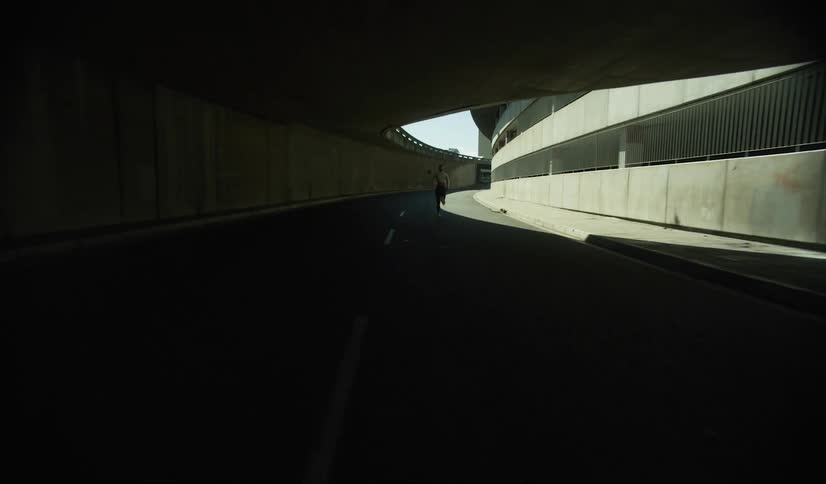 A silhouette of a person is running through a shaded tunnel