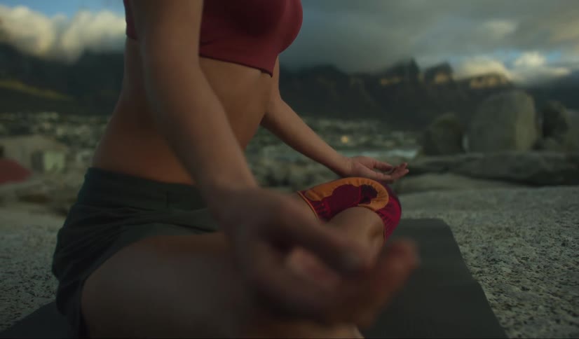 Woman sitting in a meditative pose with her hands resting on her knees amid mountains