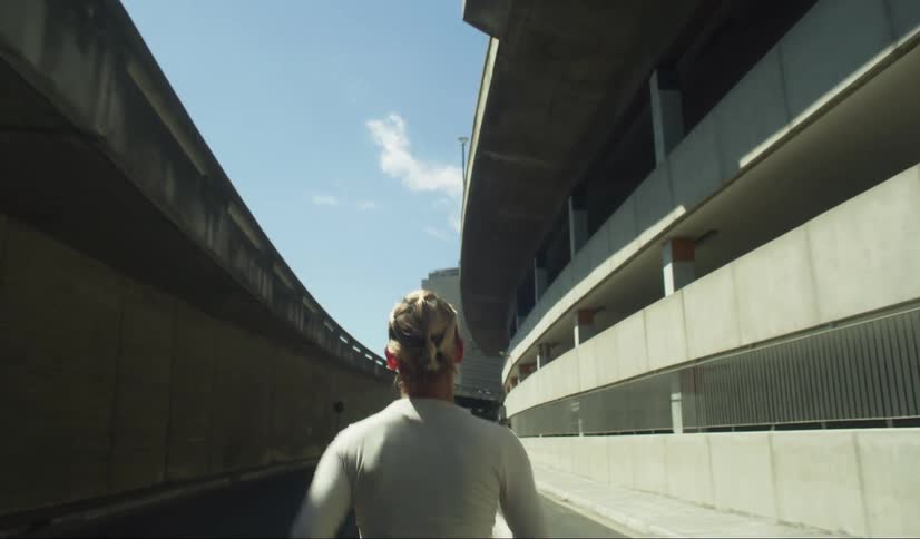 Female jogger runs down road past a parking garage on a sunny day