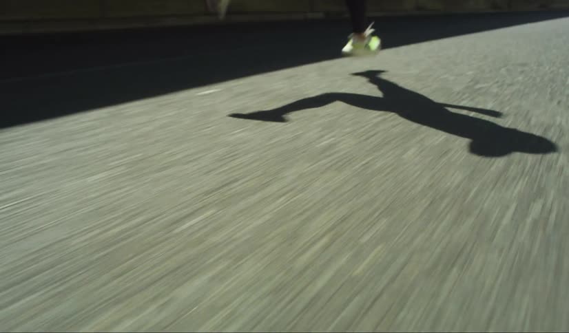 Shadow of a person running on asphalt outdoors