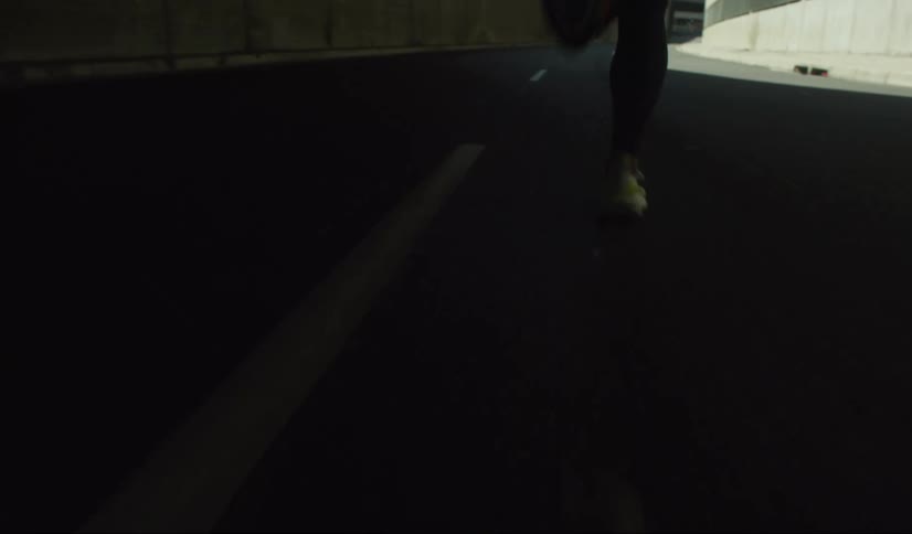 The legs of a person who is running on an asphalt street with white stripes in the middle