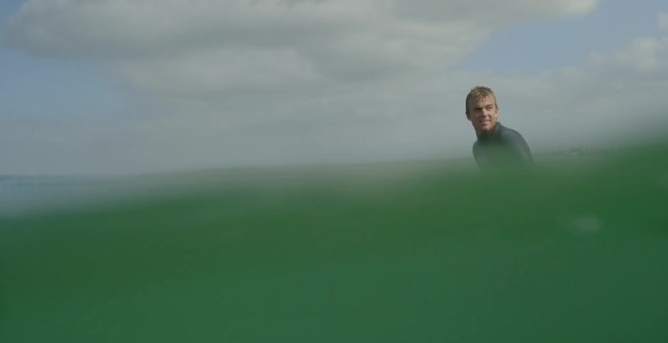 A surfer sits on his board in the ocean