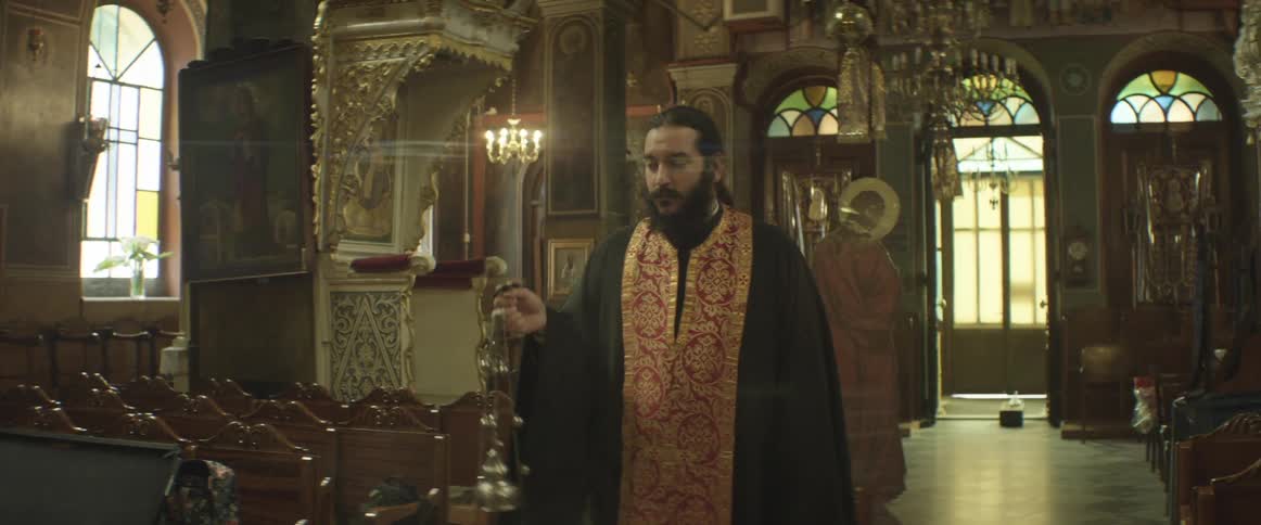 A bearded man waves a censer in church