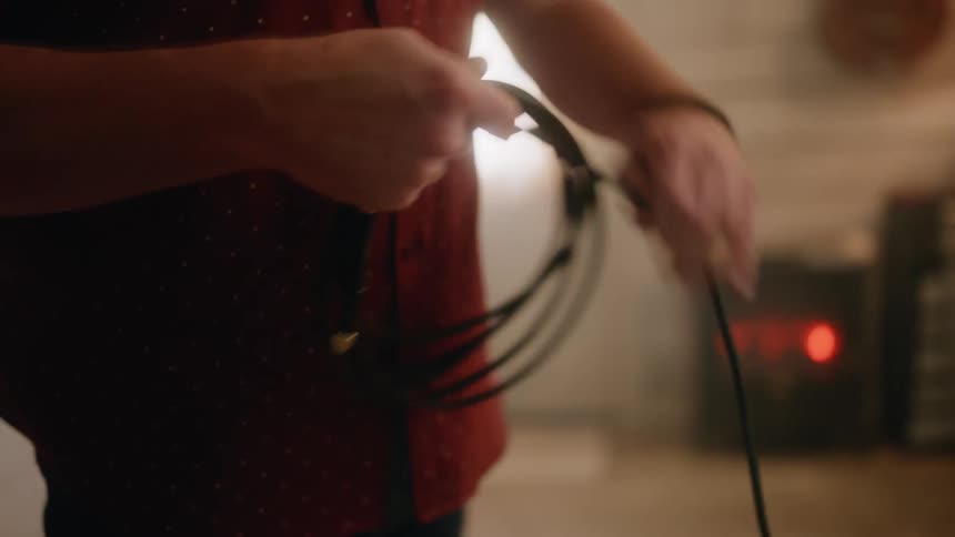 A man winds up a cord in a room