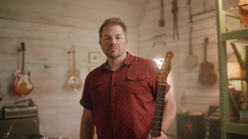 A musician standing while holding a guitar in a music studio