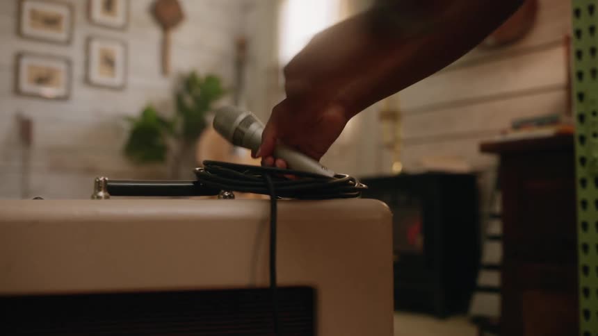 A person picks up a microphone and a cable