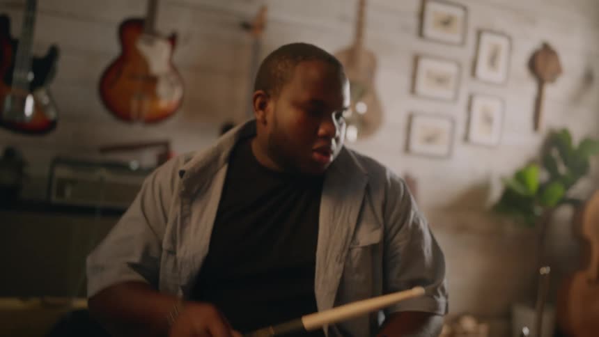 Man sitting holding drumsticks and playing drums
