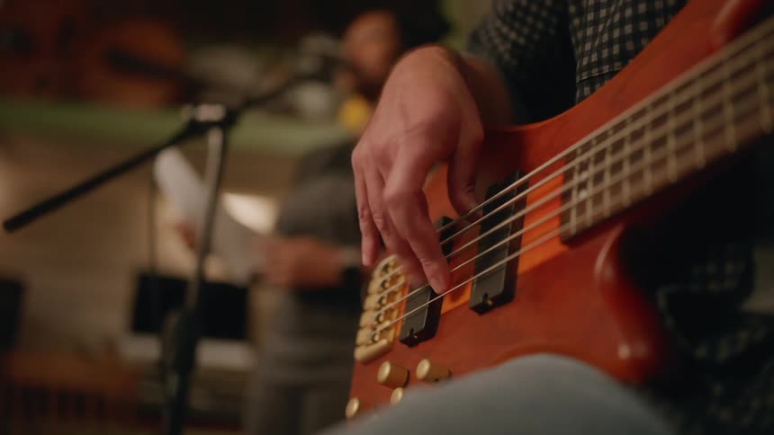 Musician playing bass guitar while the singer sings a song