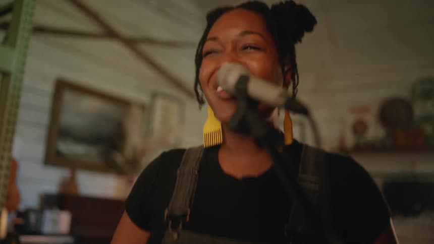 A female vocalist gestures excitedly while singing into a microphone