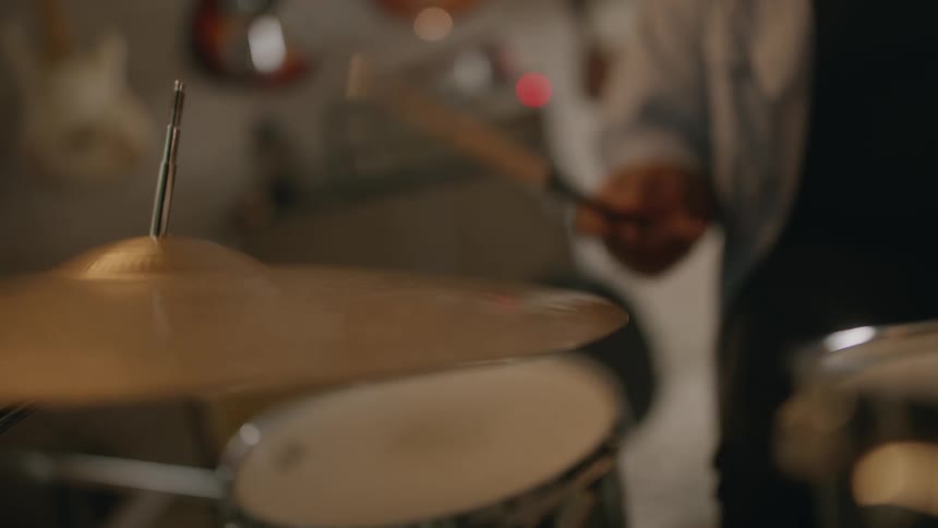 A black musician plays drums in a room