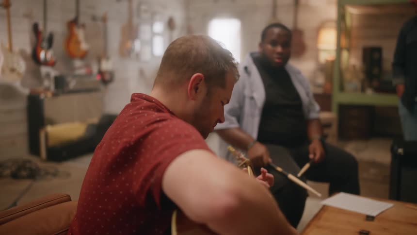 A guitarist and percussionist playing together in a studio