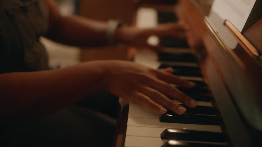 Person playing the piano focusing on the keys and finger movements