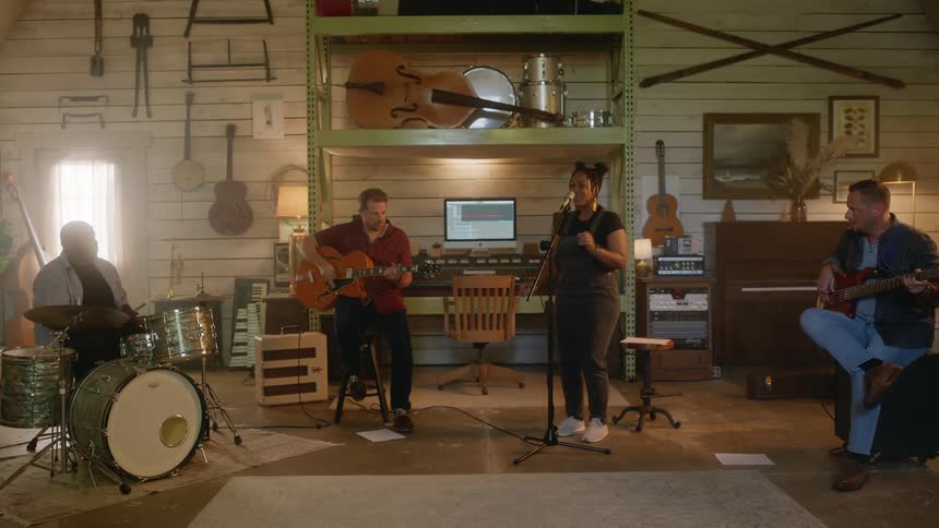 Musical band with a female vocalist singing and other drummers and guitarists in a studio