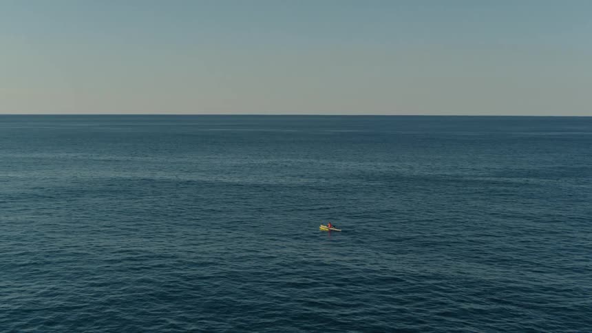 Aerial panorama of an extensive ocean with a small boat in motion