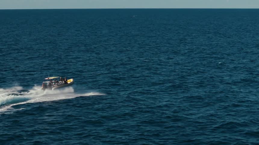 Aerial view of a boat with people traveling through the vast sea