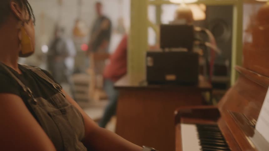 A woman plays piano while other musicians stand by