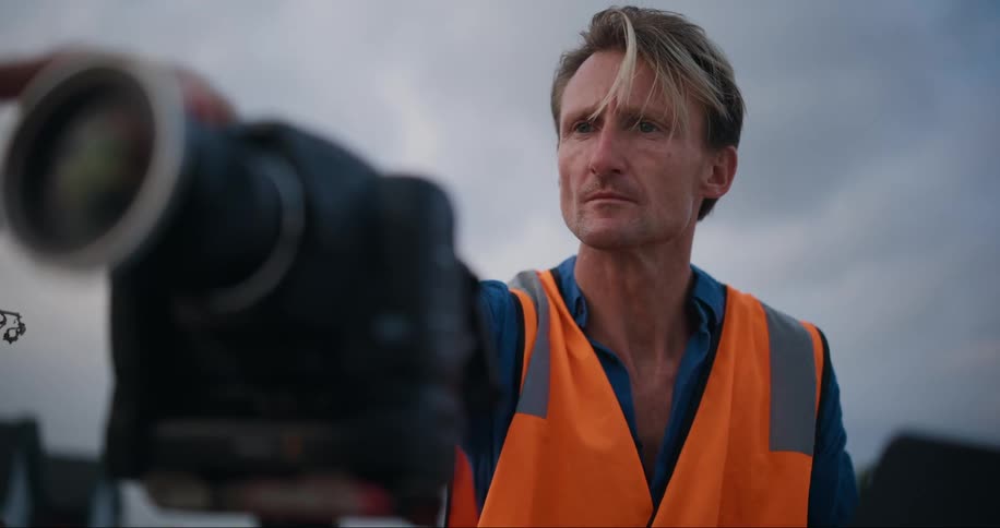 A man is using his laptop and a camera outdoors
