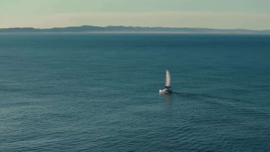 Boat sailing through the ocean on a misty day leaves a wake