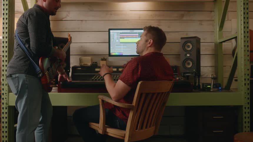 A musician with an electric guitar talking to a sound technician