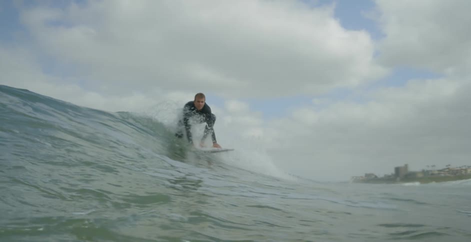 A man is riding a wave on a cloudy day