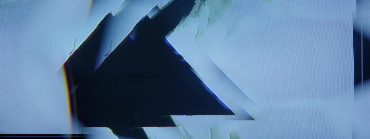 Dark translucent amorphous mass flows toward triangular shapes