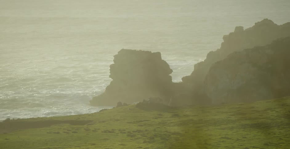 The rocks near the shore have light fog covering them