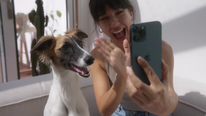 Woman talking in selfie with a smartphone accompanied by a dog at her side