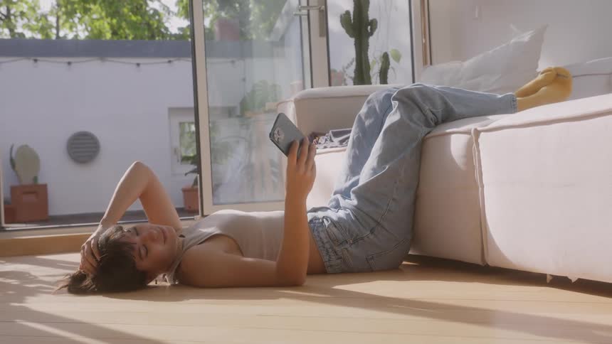 A woman is laying on the floor using her phone
