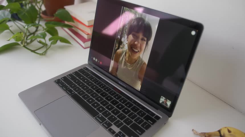 Woman appearing on a video call smiling through a laptop screen