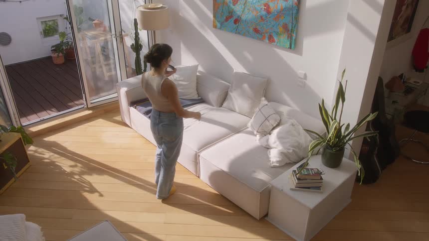 Woman talking on a smartphone walks into her living room
