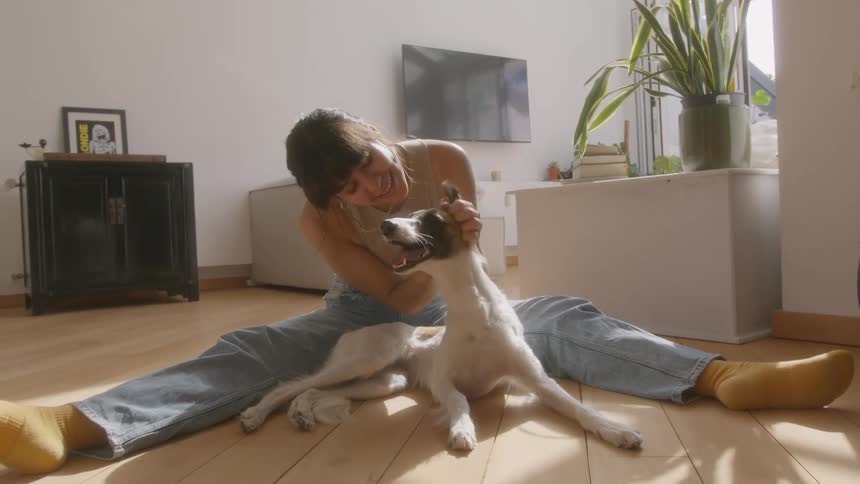 A woman smiles as she vigorously pets her dog