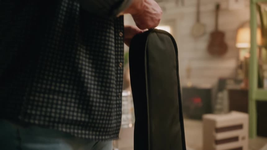A man unzips a cloth guitar case