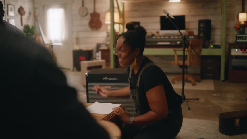 Vocalist sitting in a studio singing, vibing, and writing with other musicians