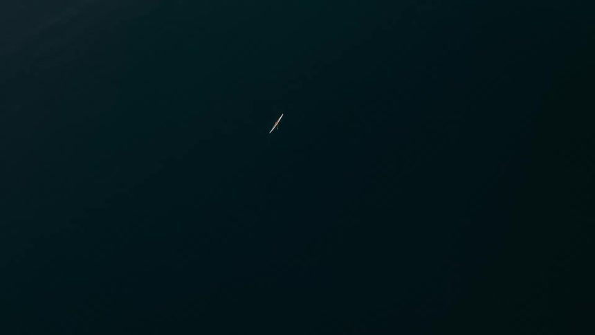 Aerial panorama of a small boat in a vast ocean