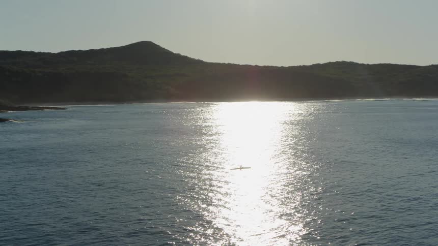 A person rows a boat near a coast