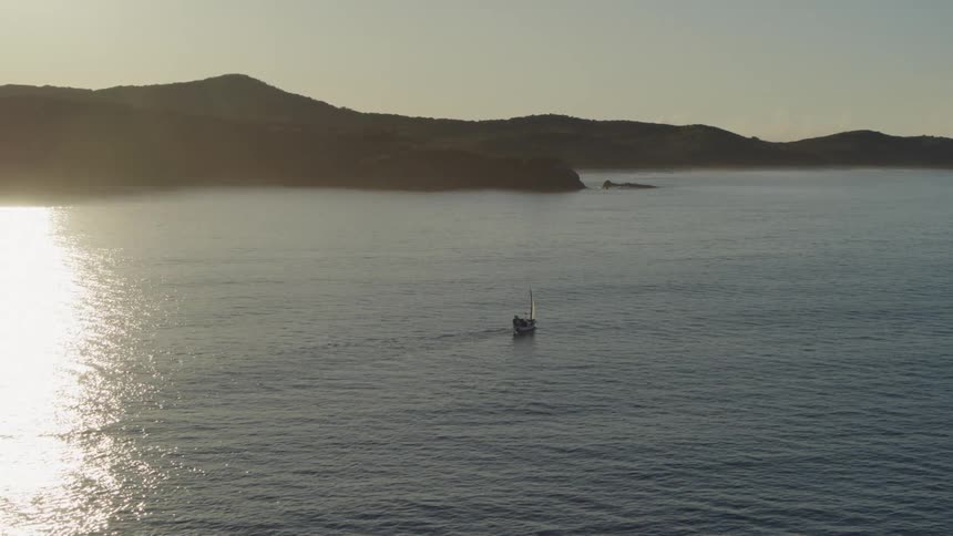 A small boat is sailing along the shore